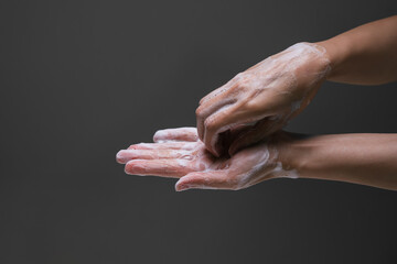 Fototapeta premium Lady washing hand rubbing with soap to prevent the spread of bacteria and virus. Personal hygiene concept. Hand wash intruction. Isolated black background. Corona virus prevention..