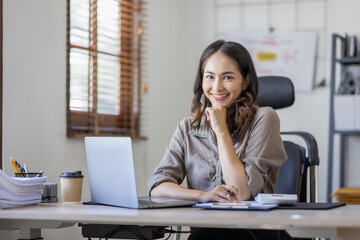Fototapeta na wymiar Young Asian businesswoman attending a virtual working financial report analysis Business Documents in workplace an home office, asian woman working contract.