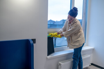 Focused cleaning lady busy dusting the room