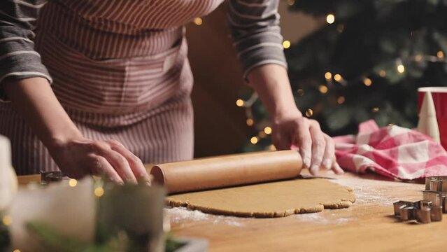Merry Christmas, Happy New Year. Gingerbread cooking, cake or strudel baking. A young woman or mother rolls out the prepared dough with a rocking chair or wooden rolling pin for cutting out cookies