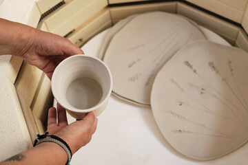close-up of hands putting vase into the kiln, oven for roasting of unbaked clay handmade products, Unfinished ceramics and utensil. Modern pottery oven ready for firing.