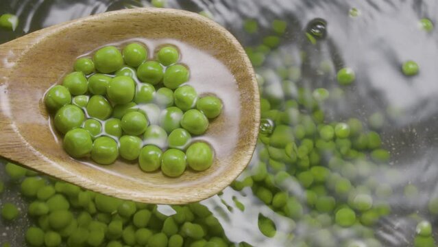 pile of green peas with a wooden spoon cooking peas in a pot. High protein legumes - healthy food, Slow motion extrime closeup shot