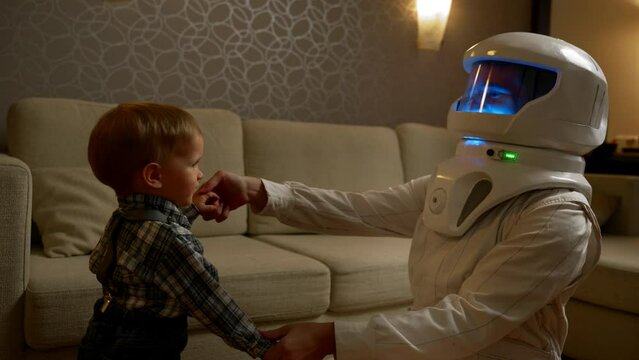 A father in an astronaut costume dances with his son toddler. The concept of the future profession of the child. It is necessary to instill a love of space in children.