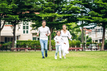 Naklejka na ściany i meble Portrait of enjoy happy love asian family father and mother holding hug cute little asian girl child smiling play and having fun run moments good time in summer park at home