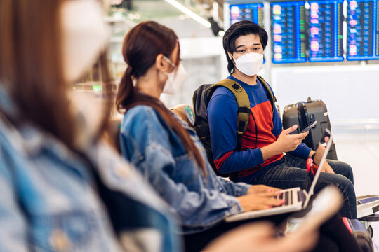 Young happy friend traveler in quarantine for coronavirus wearing surgical mask face protection hold passport and ticket before long travel vacation flight at International terminal airport
