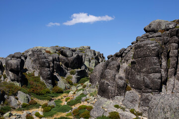 Fototapeta na wymiar Défilé montagneux aux rochers de granit arrondis et à la végétation verte et basse dans la montagne portugaise de la Serra d'Estrela.