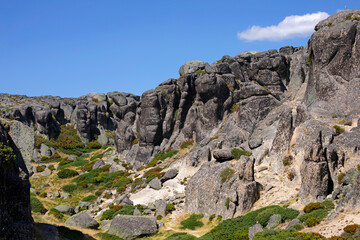 Vallon escarpé aux rochers de granit arrondis et à la végétation verte et basse dans la montagne portugaise de la Serra d'Estrela.