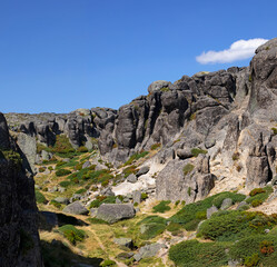 Gorge montagneuse aux rochers de granit arrondis et à la végétation verte et basse dans la montagne portugaise de la Serra d'Estrela.