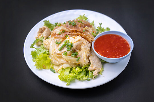 Thai food for lunch in a plate on black. Fried noodles with chiken and sqid and chili sauce