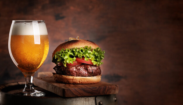 Draft beer glass and hamburger on wooden barrel
