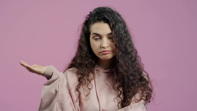 Portrait of annoyed girl making bla bla bla hand gesture expressing dissatisfaction with blabbing looking at camera on pink background