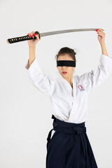 Aikido master woman in traditional samurai hakama kimono with black belt with sword, katana on white background. Healthy lifestyle and sports concept.