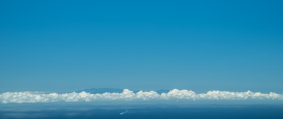 Long narrow band of cloud as a line between sky and ocean. Panoramic picture.