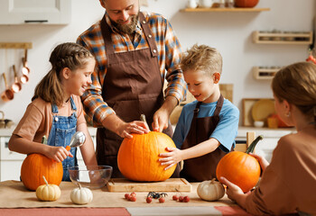 Fototapeta premium Happy family mother, father and kids to remove pulp from from pumpkin while carving jack o lantern with family