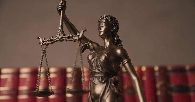 justice statue represented by blindfolded lady holding a balance and a sword signifying power and impartiality, rotating in a university room with a background made of books