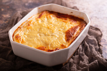 Fresh lasagna with meat and tomato sauce baked in the oven in a ceramic dish.