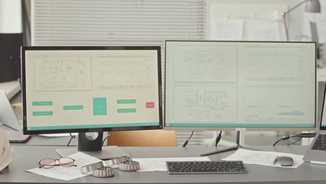 No people slowmo of two computer monitors with technology schemes on screen on work desk of design engineer in contemporary office
