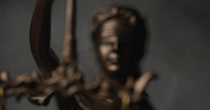 close up of bronze justice statue illustrated by blindfolded goddess holding a sword illustrating law and power 