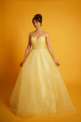 Portrait of a beautiful middle-aged woman in a yellow dress, her hair pulled up against a yellow background