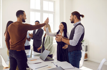 Smiling diverse businesspeople give high five celebrate shared business success. Happy employees...