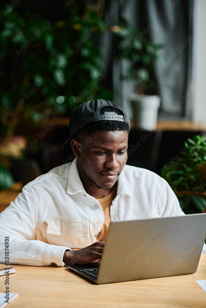 Poster young african american businessman concentrating on work with online data while sitting in front of 
