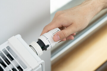 The man lowers the radiator temperature to an economical heating mode