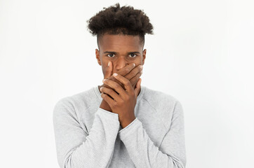 Portrait of African American man covering mouth with hands. Young bearded guy wearing white sweater...