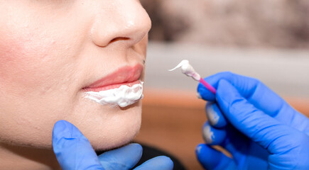 Lip augmentation. Beautician injects hyaluronic acid into the lips of a girl with a syringe. The cosmetologist doctor performs the procedure in the cosmetology office. Plastic surgery.