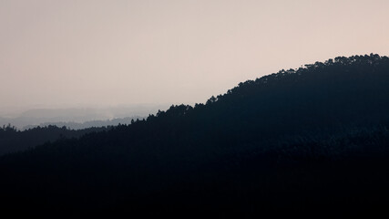 Nuit qui tombe sur les forêts de la montagne Serra d'Estrela au Portugal avec la brume qui monte de la vallée.
