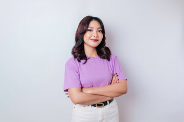 Portrait of a confident smiling Asian woman standing with arms folded and looking at the camera isolated over white background