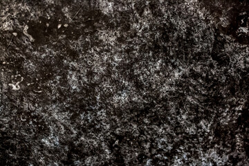 Dark background of decorative plaster with abstract spots. Unusual black or gray wall texture with beautiful patterns, creative surface background. Finishing coating for building cladding.