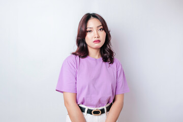 A portrait of an Asian woman wearing a lilac purple t-shirt isolated by white background looks depressed