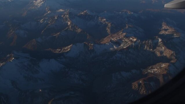 vista de la cordillera de los andes desde la ventanilla de un avion de aerolinea al atardecer con gran contraste en las monta&ntilde;as 
