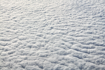 Breathtaking over clouds view from aircraft window, thick white blue clouds looks like soft foam, overcast with fresh frosty air. Beautiful cloudy sky view to troposphere, heavy cloudiness - obrazy, fototapety, plakaty