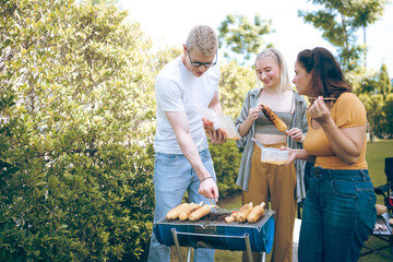 Obraz premium Happy family cheering with barbecue dinner outdoor - Group of people having fun at weekend meal - BBQ Food, taste and summer concept, Man cooking meat on barbecue grill at summer party