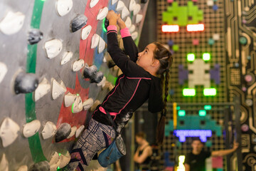 Obraz na płótnie Canvas bouldering, little girl climbing up the wall