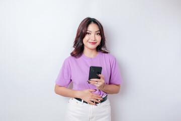 Pleased smiling Asian woman keeps hand on belly feels happy after ordering food by phone