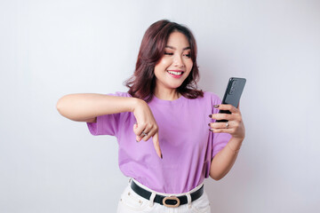 Naklejka premium Smiling beautiful Asian woman pointing finger down to empty space isolated white background