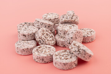 Heap of medicine colored pills, tablets on a pink background