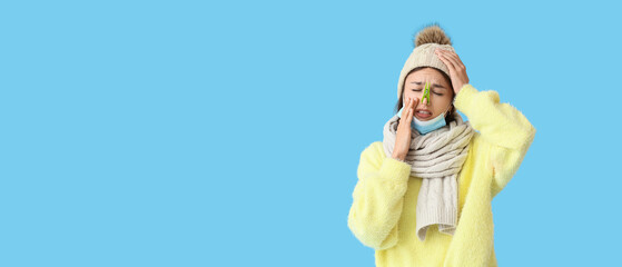 Ill young woman with clothespin on her nose against blue background with space for text