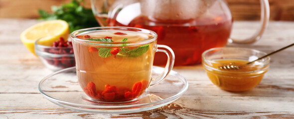 Cup of hot goji tea on wooden table