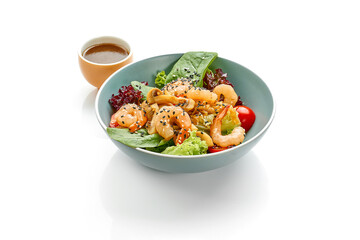 Green salad with shrimp, mushrooms and tomatoes in a bowl on a white background.