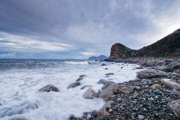 Beautiful landscape with rock sea beach and cloudy sky.