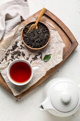 Composition with dry tea leaves and cup of hot beverage on white background