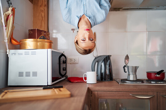 Young Woman At Upside Down Kitchen.