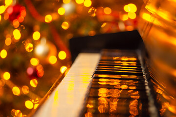 Close-up shot of keyboard of piano with bright lights of garlands on the background. Christmas...