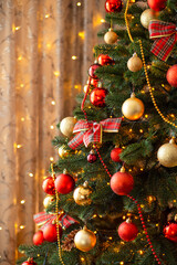 Close-up vertical shot of decorated Christmas tree. Fir tree in golden and red baubles, lights, celebrating New Year