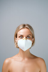 Portrait of a young woman in a medical mask on a grey background.