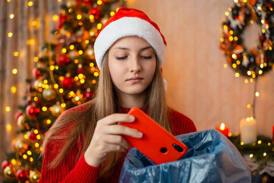 Unhappy Girl Throws Away Red Mobile Phone Present From Friend, Dissatisfied With Christmas Present, Sad To Receive Not The Latest Gadget. Bad Unwanted Present For Christmas Concept