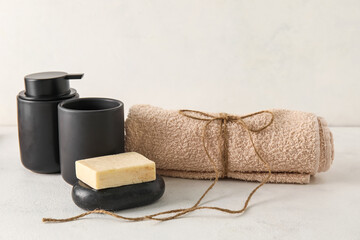 Fototapeta na wymiar Set of bath supplies with towel on light background